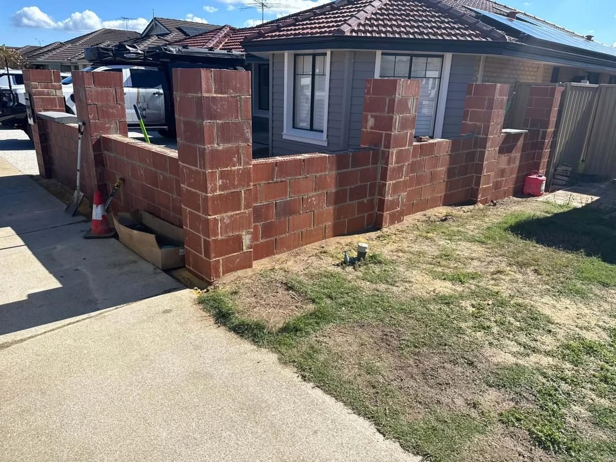 Bare red brick boundary wall before rendering